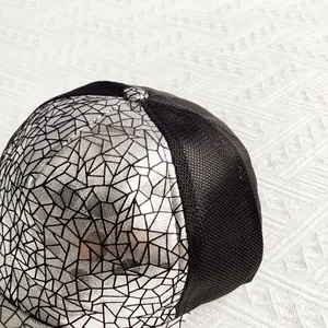 Macro detail of silver cracked pattern fabric and breathable black mesh on baseball cap