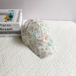 Détail d'une casquette en dentelle blanche avec motifs floraux oranges et fleurs 3D en tissu