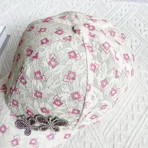 Close-up of lace baseball cap featuring pink geometric patterns and rhinestone butterflies