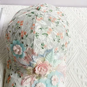 Détail d'une casquette en dentelle florale avec fleurs en tissu et perles délicates
