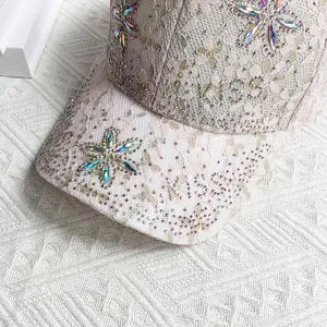 Détail de la dentelle blanche et des fleurs en strass colorés sur une casquette rose