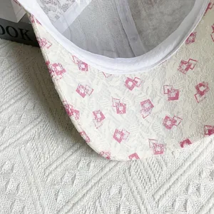 Close-up of white lace baseball cap brim featuring pink geometric pattern and fine textures