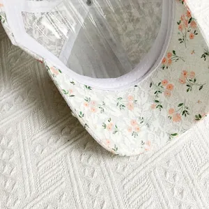 Close-up of white lace baseball cap featuring intricate floral embroidery and inner lining