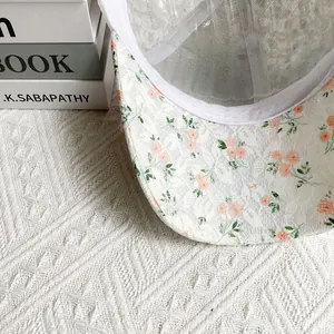 Gros plan détaillé sur casquette en dentelle blanche avec broderies florales orange