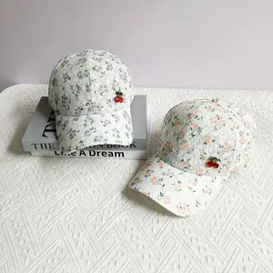 Detail of floral lace baseball cap featuring decorative red cherry ornaments and embroidery