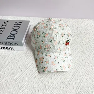Detailed close-up of white lace floral baseball cap with a red cherry charm accent