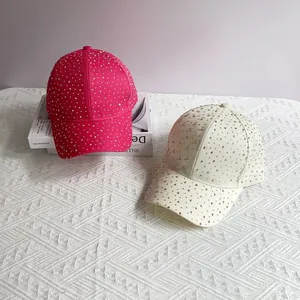 Fashionable sparkling rhinestone baseball caps in rose red and beige on a white knit background