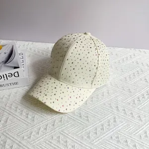 Detailed view of shimmering AB rhinestones on a cream white fashion baseball cap