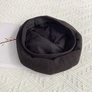 Detail view of black wool octagonal beret with vertical rhinestone stripes and inner lining