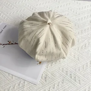 Detailed view of the cream wool beret featuring vertical silver rhinestone stripes