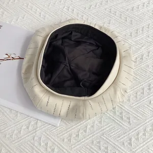 Detail of beige wool beret with vertical rhinestone stripes on soft textured background