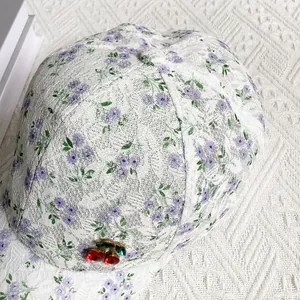 Detail of white floral lace baseball cap featuring a decorative cherry rhinestone accent