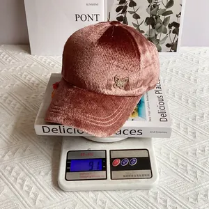 Dettaglio del cappellino in velluto rosa con spilla a farfalla dorata e trama a coste