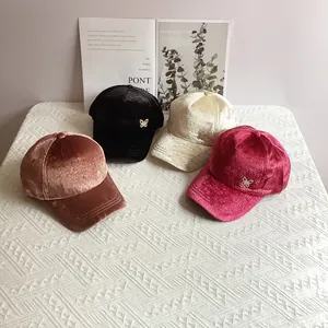 Dettaglio ravvicinato di cappelli da baseball in velluto con farfalla di strass