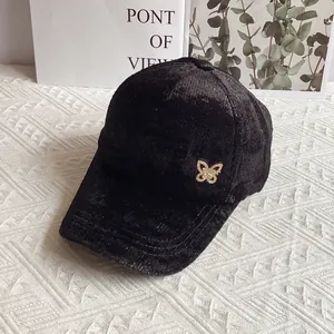 Dettaglio del berretto da baseball in velluto nero con decorazione a farfalla scintillante