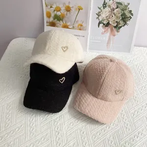 Détail de casquettes en peluche alpaga en blanc, noir et rose avec breloque cœur en strass