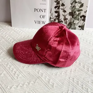 Dettaglio del cappello in velluto rosa con farfalla di strass e trama a costine