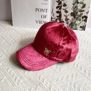Dettaglio del berretto in velluto bordeaux con emblema a farfalla di strass scintillanti