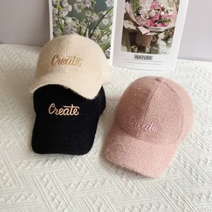 Dettaglio dei cappellini in ciniglia felpata nei colori panna, nero e rosa con ricamo