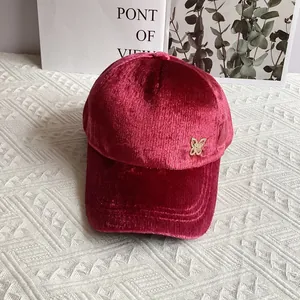 Dettaglio del cappellino in velluto rosa con emblema a farfalla dorata con strass