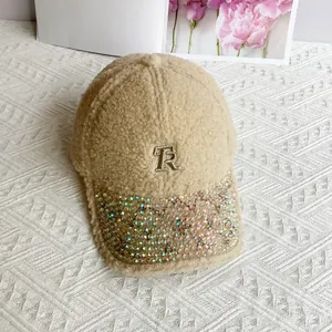 Close-up of beige teddy fleece baseball cap with gold TR embroidery and AB rhinestones