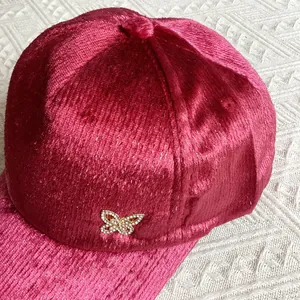 Primo piano del berretto da baseball in velluto rosa con dettaglio farfalla