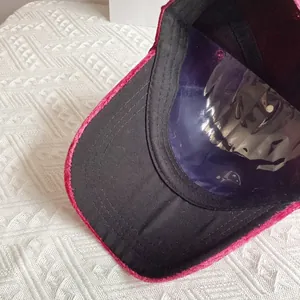 Dettaglio della trama in velluto e cuciture sulla tesa di un berretto da baseball fucsia