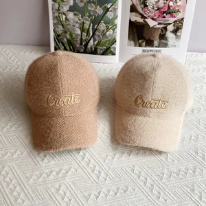 Dettaglio dei cappellini da baseball in ciniglia con ricamo Create in cammello e beige