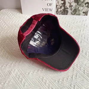 Dettaglio ravvicinato del cappellino da baseball in velluto rosso scuro regolabile