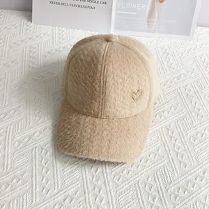 Détail de la casquette beige en laine d'alpaga avec un accent métallique en cœur doré