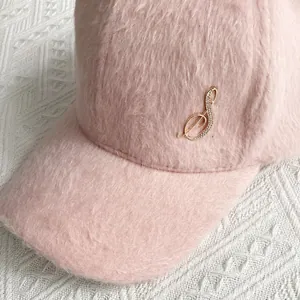 Close-up of light pink plush velvet baseball cap with rhinestone musical note logo detail