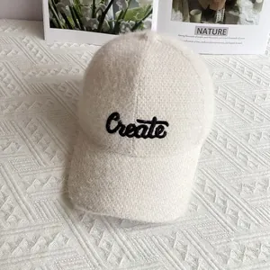 Dettaglio del cappello da baseball in ciniglia crema con ricamo nero della scritta Create
