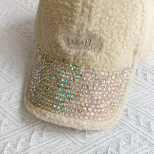 Dettaglio della visiera con strass e ricamo Take Off su cappello in pile beige