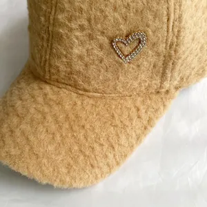 Gros plan sur casquette baseball en polaire camel avec un détail cœur en strass brillants