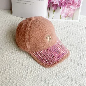 Close-up of pink sherpa baseball cap with golden TR embroidery and rhinestone brim