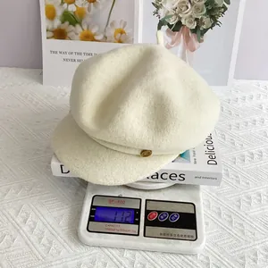 Gros plan sur la casquette en laine crème de 112g avec détail de petit bouton doré