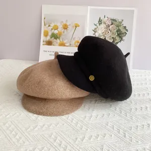 Détail de bérets en laine kaki et noirs avec accents dorés et texture douce et épaisse