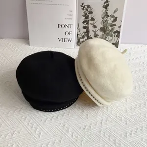 Detail shot of felt beret hat with metallic rivets in black and cream beige tones