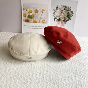 Woolen beret hats for women in cream and red with metallic butterfly emblem detail
