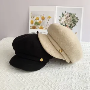 Détail de casquettes gavroche en laine noire et beige avec boutons dorés élégants