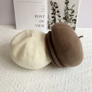 Detail of wool beret hats in cream and dark coffee colors with elegant beaded rim decoration
