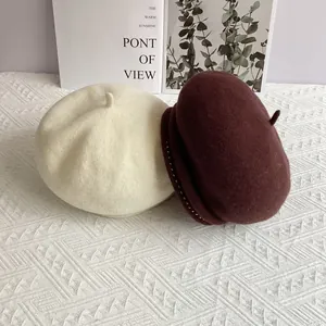 Detailed texture of wool felt berets in beige and burgundy with small metal beads