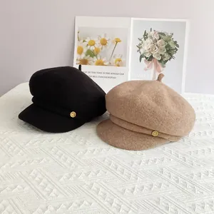 Détail de casquettes gavroche en laine noir et kaki avec boutons dorés métalliques