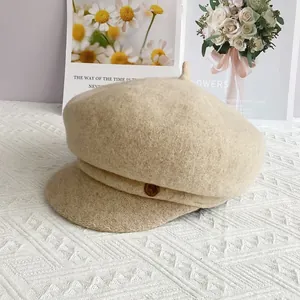 Détail de la casquette gavroche en laine beige avec texture et bouton latéral décoratif