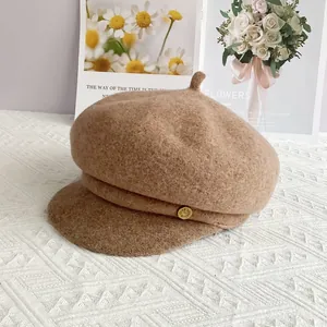 Détail d'une casquette en laine avec plaque dorée et visière courte rigide