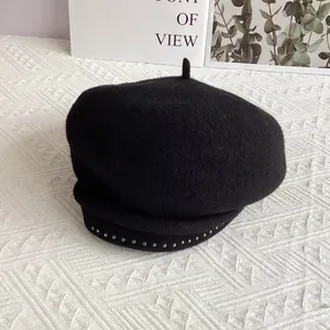 Detail shot of black wool beret featuring silver metal studs and textured fabric
