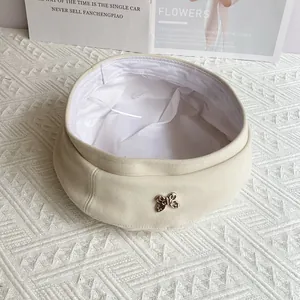 Detailed close-up of cream wool beret featuring a silver metal butterfly accent
