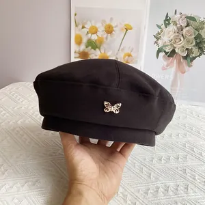 Close-up of black wool beret with a decorative golden butterfly metallic accent