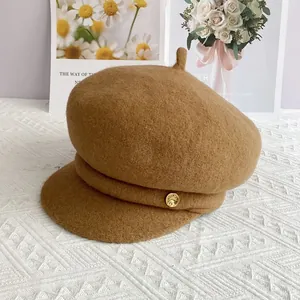 Détail de la casquette gavroche en laine camel avec bouton doré et sangle en tissu