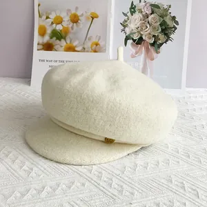 Détail du béret en laine crème avec bouton doré et texture de tissage épaisse et douce